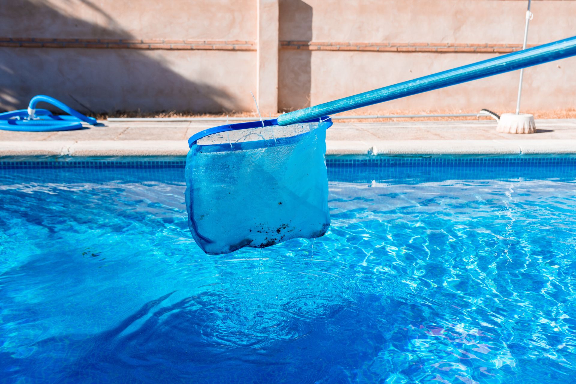 Skimmer net cleaning debris from a pool during professional pool maintenance in Waterloo.