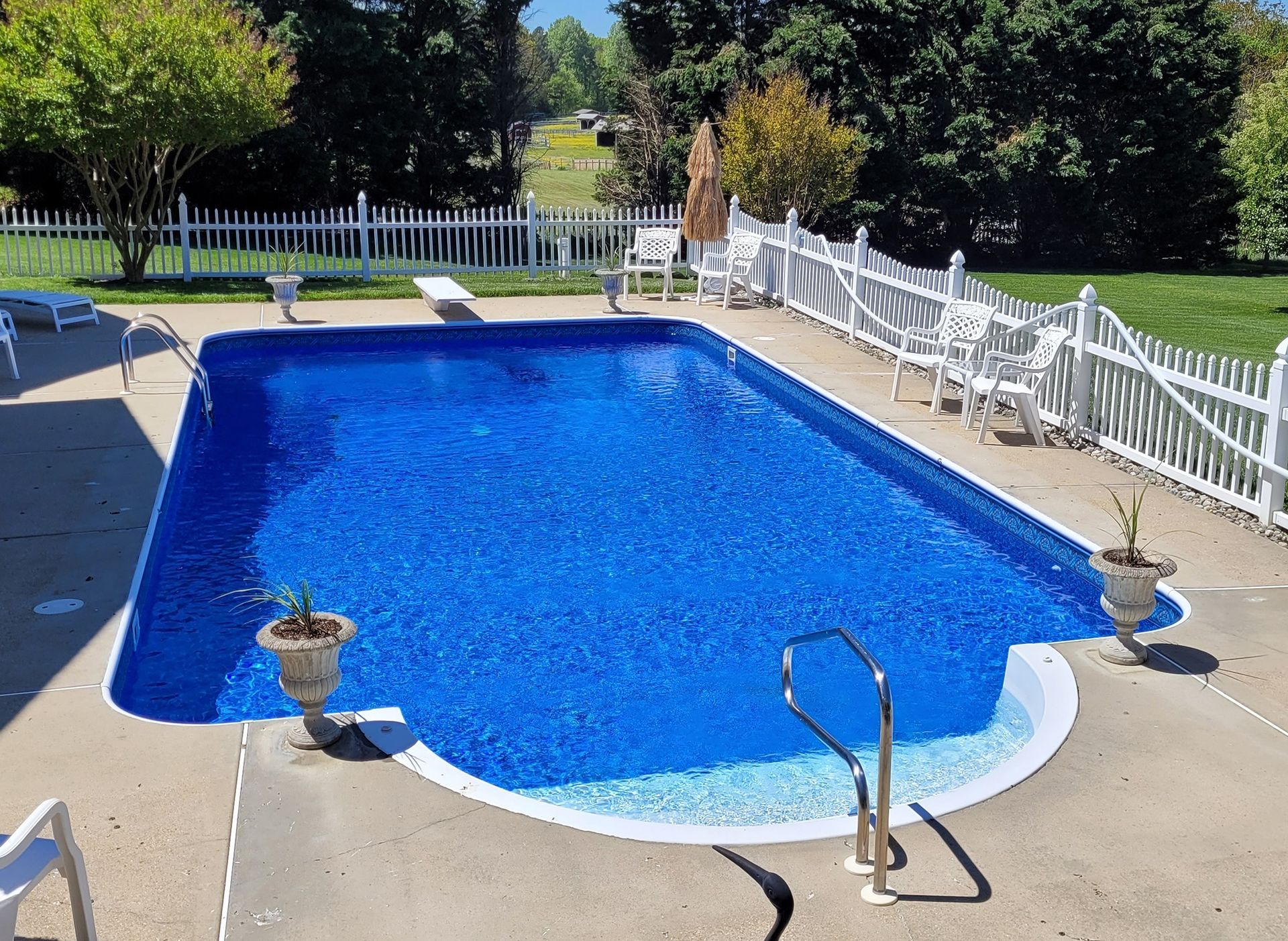 A professionally remodeled inground swimming pool with a new liner, surrounded by a clean deck and white fencing, perfect for a backyard upgrade.