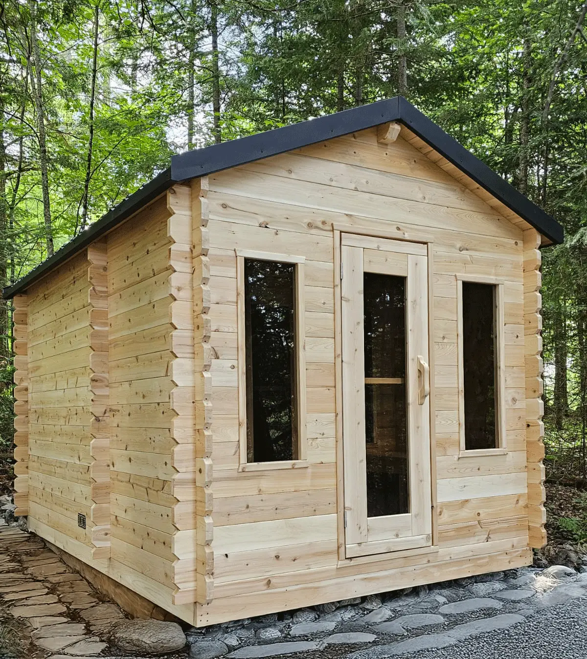 Outdoor wood sauna cabin with glass door and windows in a forest setting