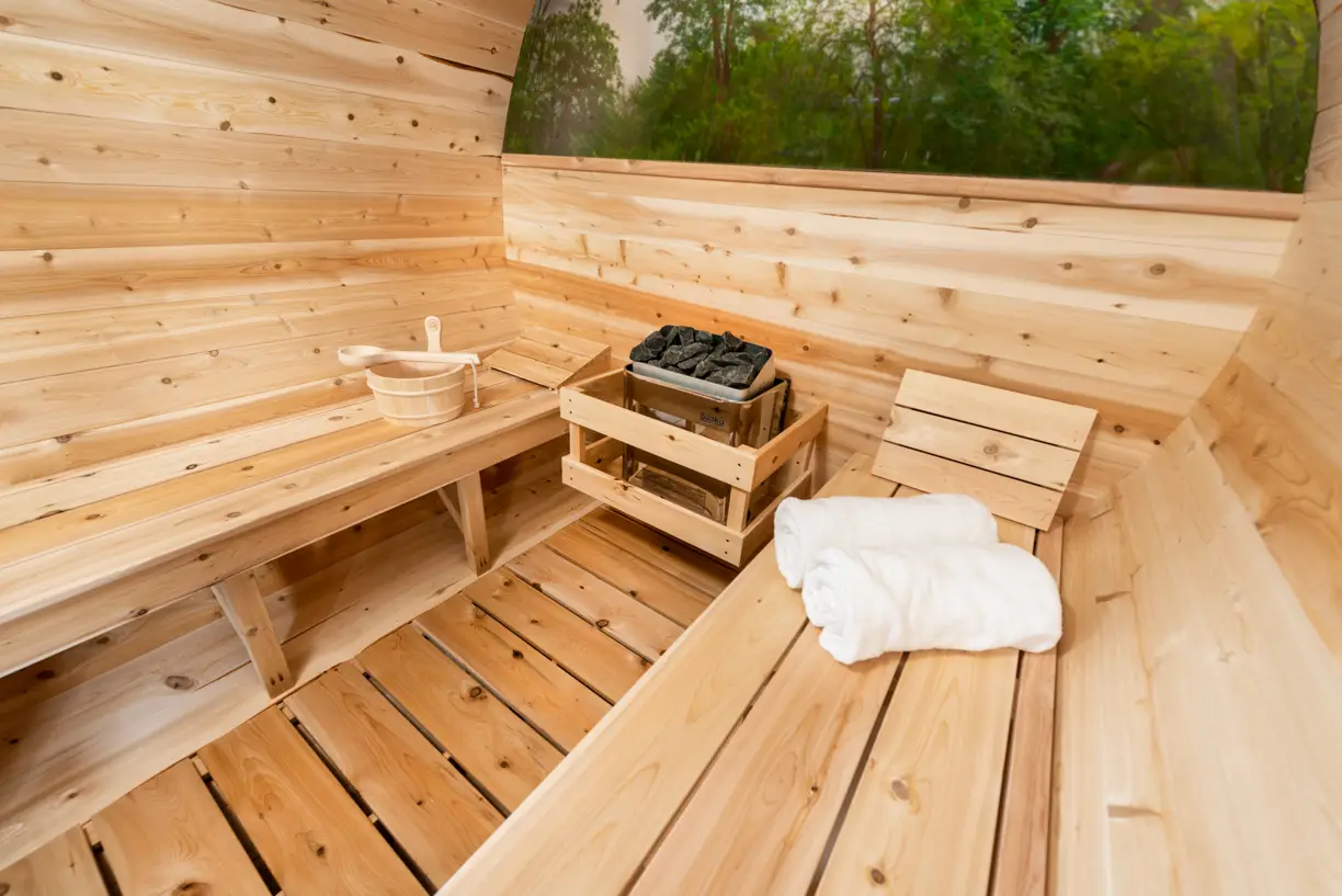Interior of a LeisureCraft outdoor sauna showing cedar benches, heater, and traditional sauna accessories